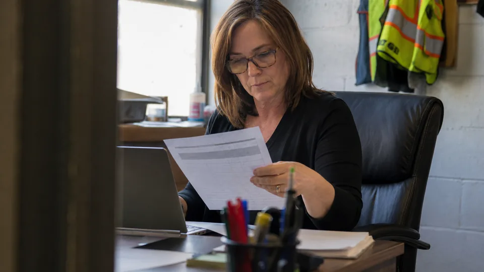 HR manager reviewing a printed employee training checklist beside a laptop